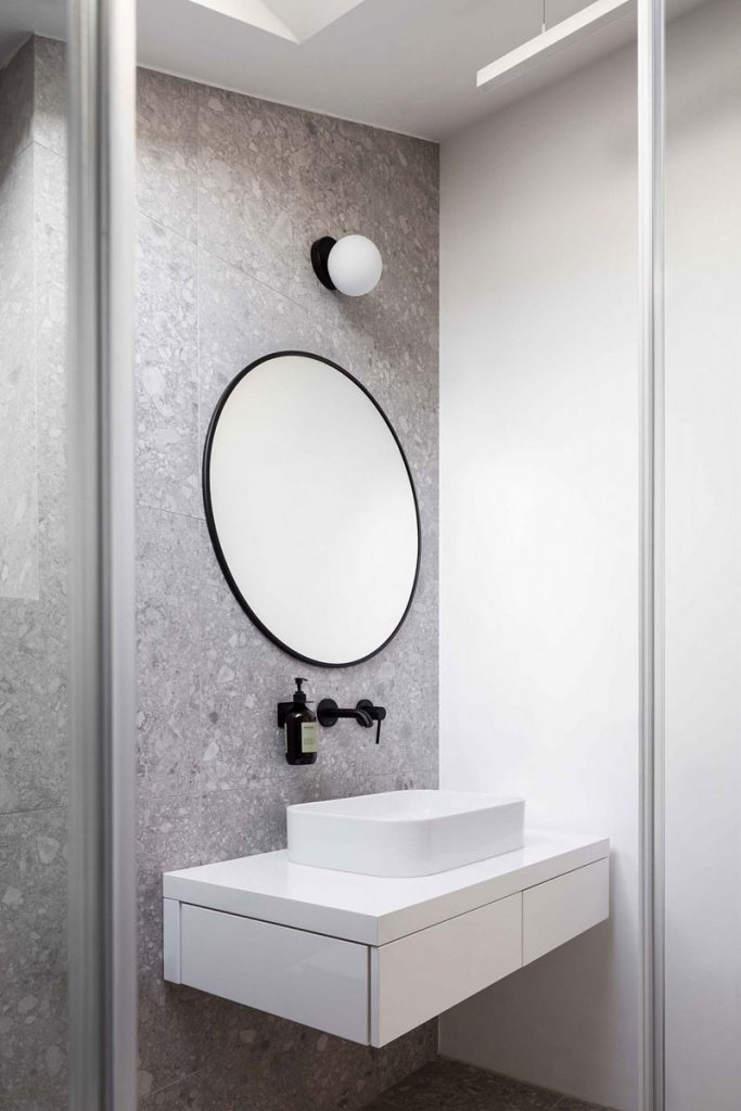 badkamer grote ronde spiegel grijze terrazo tegels wand