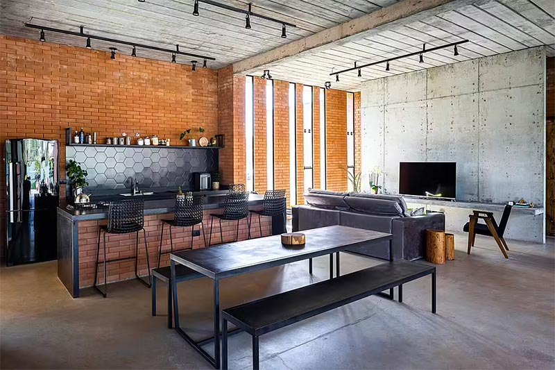 Taguá Arquitetura e Design heeft voor deze industriële keuken gekozen voor een stoere betonnen vloer, die eigenlijk uitstrekt over de gehele leefruimte met woonkamer en eethoek.