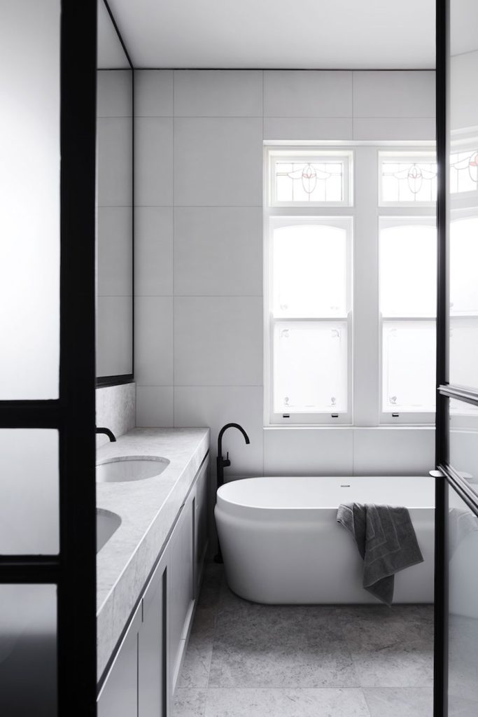 Ontwerpbureau Mim Design combineerde zwarte kranen en een dubbele wastafel van marmer in deze luxe badkamer.