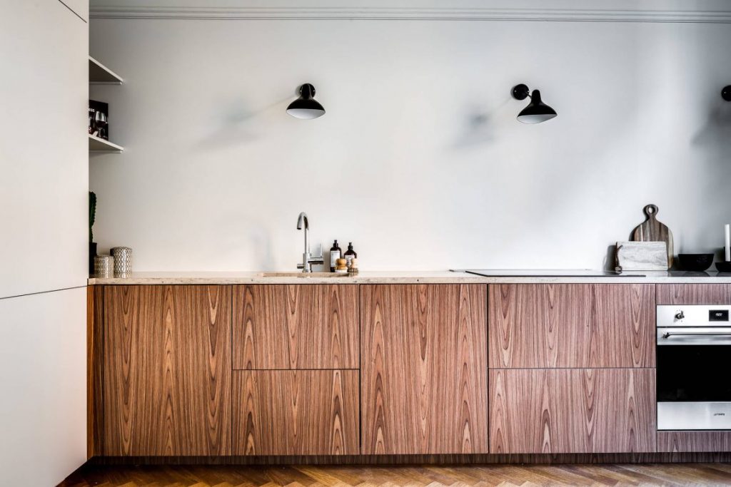Houten keukenkasten en een strakke gestucte keuken achterwand voor een minimalistische look met zwarte wandlampen.