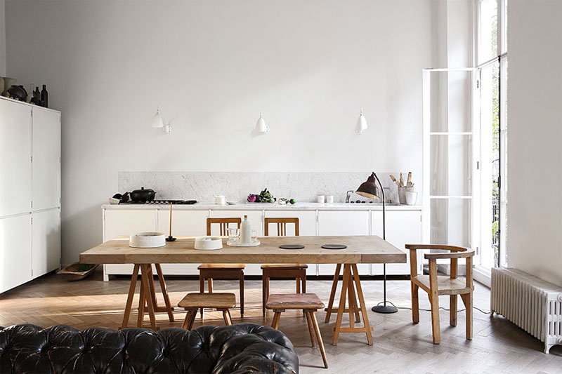 In deze open keuken is er gekozen voor een grote houten eettafel met houten krukjes en stoelen eromheen.