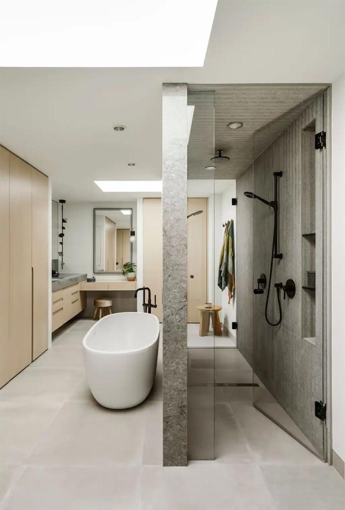 De op maat gemaakte inbouwkasten passen perfect bij de luxe uitstraling in het ontwerp met zowel een ruime inloopdouche als een vrijstaand bad.