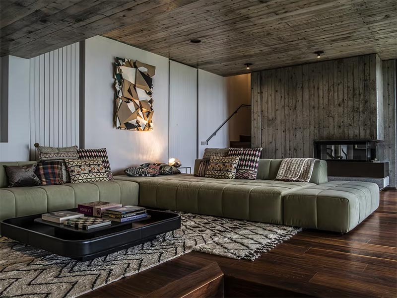 Studio Atelier P heeft in deze mooie rustieke woonkamer hetzelfde hout gebruikt voor zowel het plafond als de ombouw van de haard. 