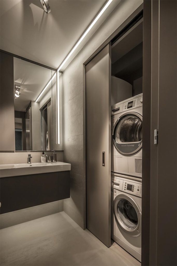 Deze moderne kleine badkamer is ontworpen door Suto Interior Architects, die een grote inbouwkast heeft gecreëerd voor de droger en wasmachine.