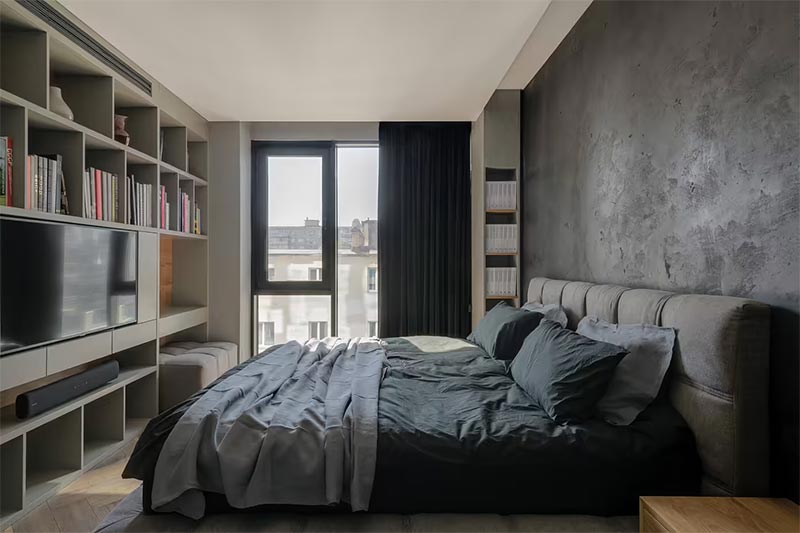 De strakke inbouwkast vormt een mooi contrast met de industriële betonlook muur achter het bed.