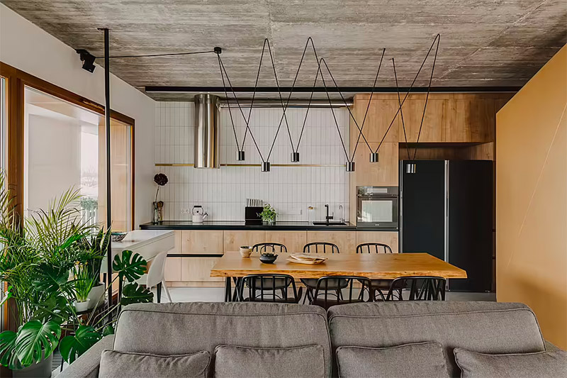 Dit stoere appartement, ontworpen in 2020 door de getalenteerde Mili Młodzi Ludzie, is geïnspireerd op de betoverende stad Monsanto in Portugal. De woonkamer is modern, maar heeft dankzij verschillende details ook een heel stoer industrieel tintje, zoals het betonnen plafond, en meubels van hout en staal. | Fotografie: ONI Studio