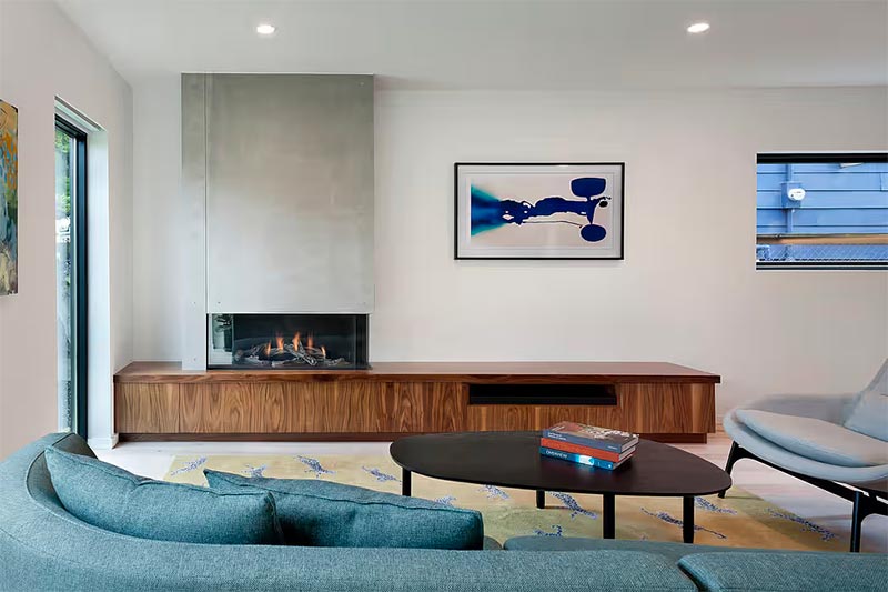 First Lamp Architects koos in deze mooie woonkamer om de muur van de inzethaard te bekleden met stoere beton cire. Het vormt een mooie combinatie met de houten TV meubel eronder.