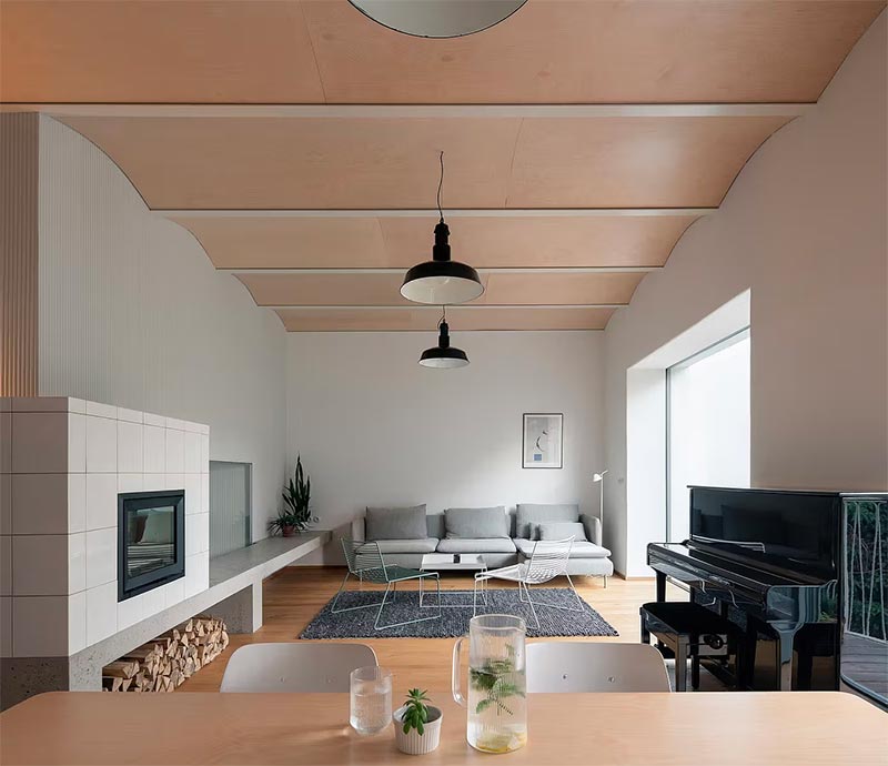 Deze moderne woonkamer is ontworpen door BYRÓ architekti, waar gekozen is voor een strakke inzethaard met een betegelde ombouw. | Fotografie: Alex Shoots Buildings