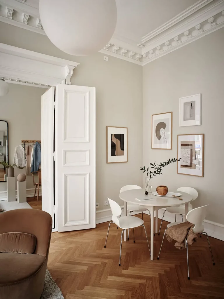 In dit statige appartement, gekenmerkt met authentieke details, is er een passende visgraat houten vloer gekozen, in combinatie met klassieke hoge witte plinten.