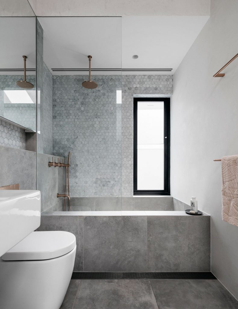 In plaats van een douchegordijn, kozen de ontwerpers van Alexander &CO voor een glazen douchewand op het bad in deze mooie kleine badkamer. Klik hier voor meer foto's.