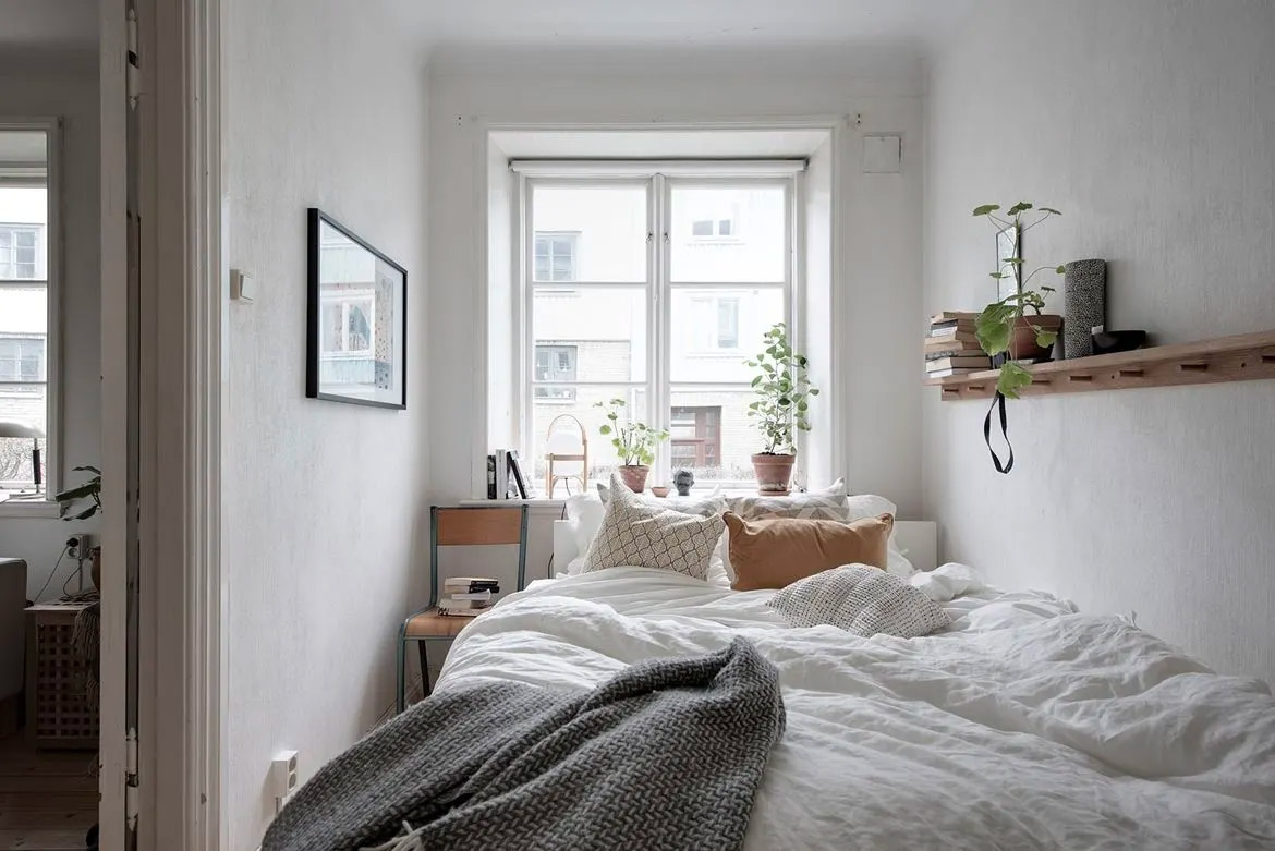 Heb je geen ruimte voor een kast? Een wandplank kan altijd! In deze super kleine slaapkamer maken ze ook goed gebruik van de vensterbank!