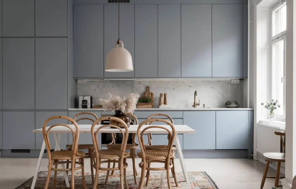 De minimalistische lichtblauwe keukenkasten zorgen voor meer ruimtelijkheid in deze kleine leefruimte.
