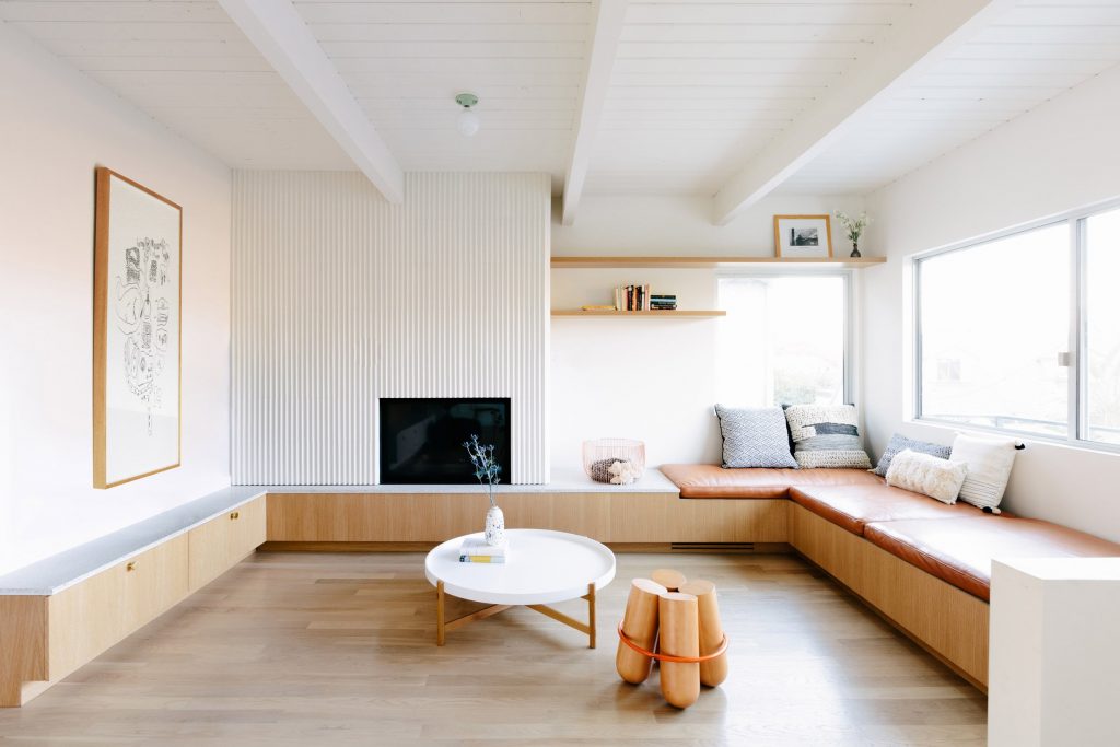 Interieurontwerpers Annie Ritz en Daniel Rabin creëerde deze ruime zithoek van een fijne lichte L-vormige woonkamer, met een op maat gemaakte meubel, dat een vaste bank, TV meubel en open haard combineert.