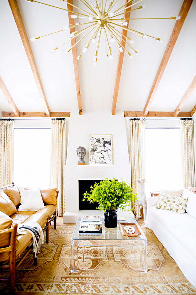 Super mooie woonkamer waar een vintage leren bank gecombineerd is met een mooie witte bank, en een glazen salontafel.Fotografie: Brittany Ambridge