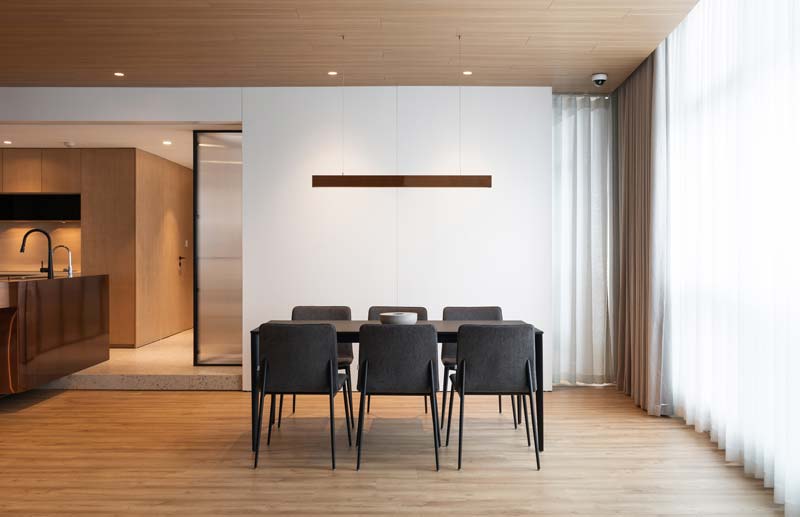 In deze moderne eethoek is een strakke lineaire hanglamp boven de rechthoekige eettafel opgehangen. Klik hier voor meer foto's.