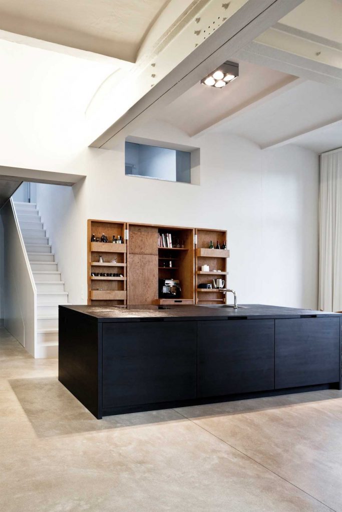 Deze moderne minimalistische keuken is ontworpen door Duitse architect Thomas Bendel met strakke witte muren, betonlook vloer en combinatie van zwarte en houten keukenkasten. Klik hier voor meer foto's.