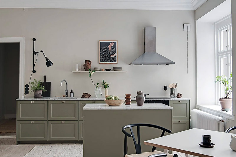 Een super mooie olijfgroene keuken met eiland, groene kasten en een wit marmeren werkblad.