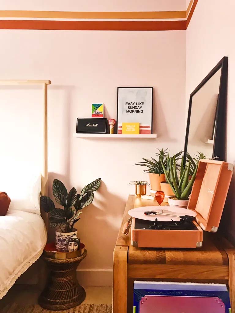 Dit is de super leuke retro slaapkamer van Emma van freelance kunstconsulent, interieurstylist en meermaals bekroonde blogger die woonachtig is in de mooie Costa del Margate. Naast prachtige roze muren met vintage gekleurde lijnen en mooie meubels, heeft ze ook een geweldige retro platenspeler in haar slaapkamer. Klik hier voor meer foto's.