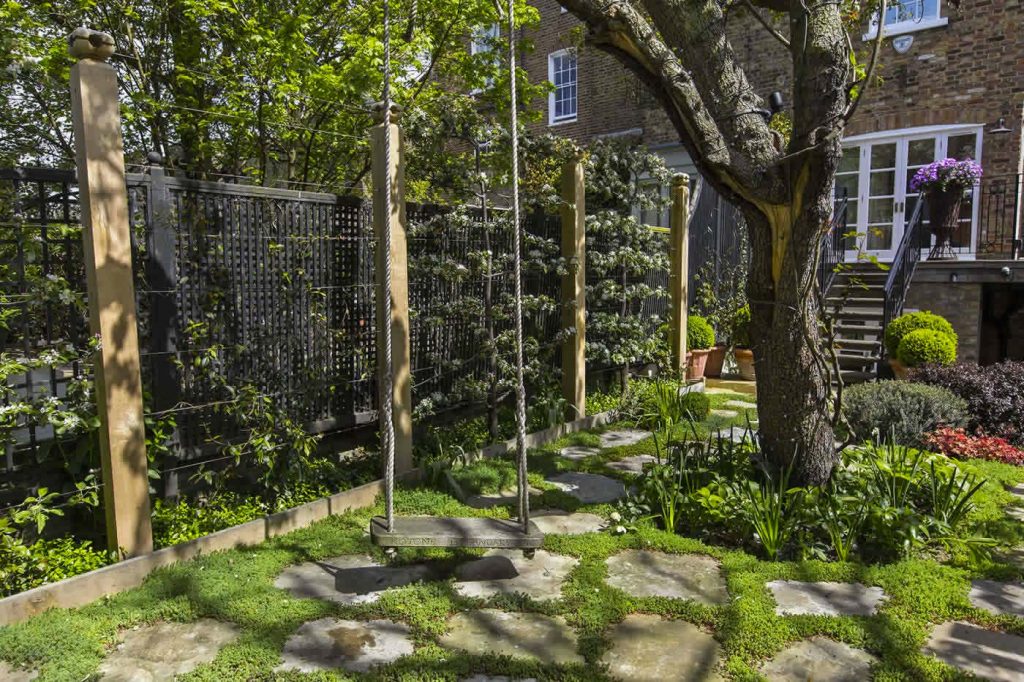 In deze mooie romantische tuin, ontworpen door Gardenbuilders.co.uk is een schommel onder de grote boom opgehangen.
