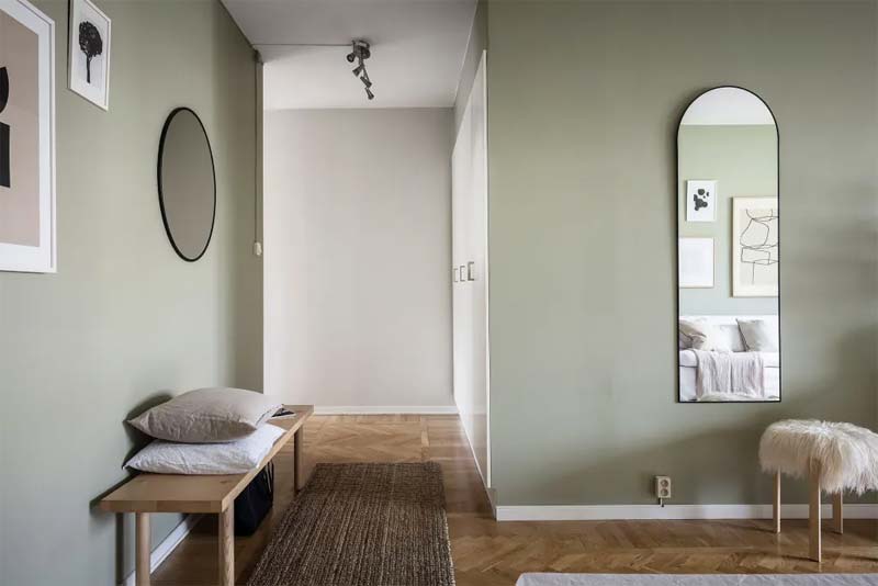 Prachtige combinatie van sage green muren, visgraat houten vloer, houten meubels en zwarte accenten aan de muur.