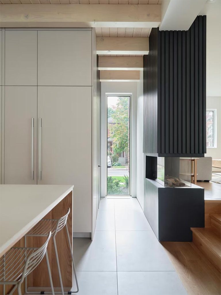 Salem Architecture gebruikte een mooie sfeerhaard als een soort roomdivider tussen de woonkamer en open keuken in deze moderne woonkamer. | Fotografie: Phil Bernard