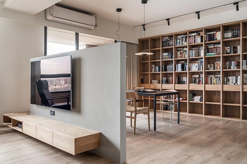 Bigsense Design Studio koos voor een halfhoge scheidingswand waar de TV aan opgehangen is, tussen de woonkamer en de ruime eethoek. | Fotografie: YHLAA