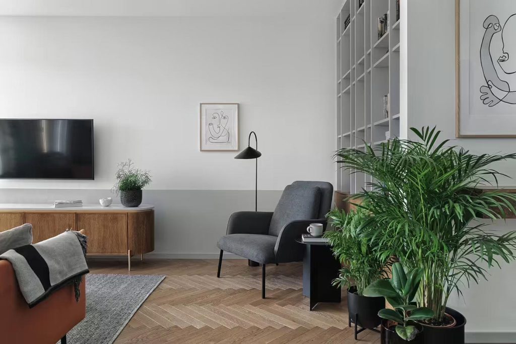 Raca Architekci laat zien dat het ook heel mooi kan zijn om de TV aan de muur te combineren met een TV meubel met pootjes. De TV is net boven de geschilderde lambrisering opgehangen. | Fotografie: Tom Kurek