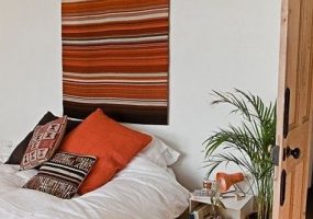 Klein vloerkleed aan de muur boven het bed