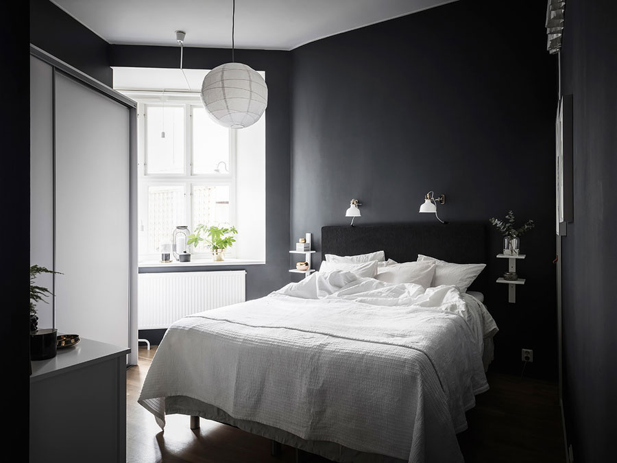 Een zwevend nachtkastje kan ook gewoon een wandplank zijn die je naast je bed ophangt. In deze zwarte slaapkamer zijn aan weerszijden witte zwevende wandplankjes opgehangen met twee lagen.