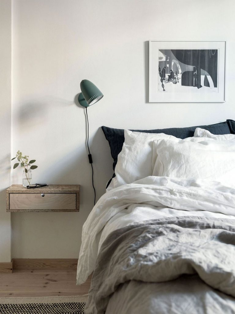 Dit zwevende nachtkastje met lade, gemaakt van OSB planken, hangt op dezelfde hoogte als het matras naast het bed in deze Hygge slaapkamer.